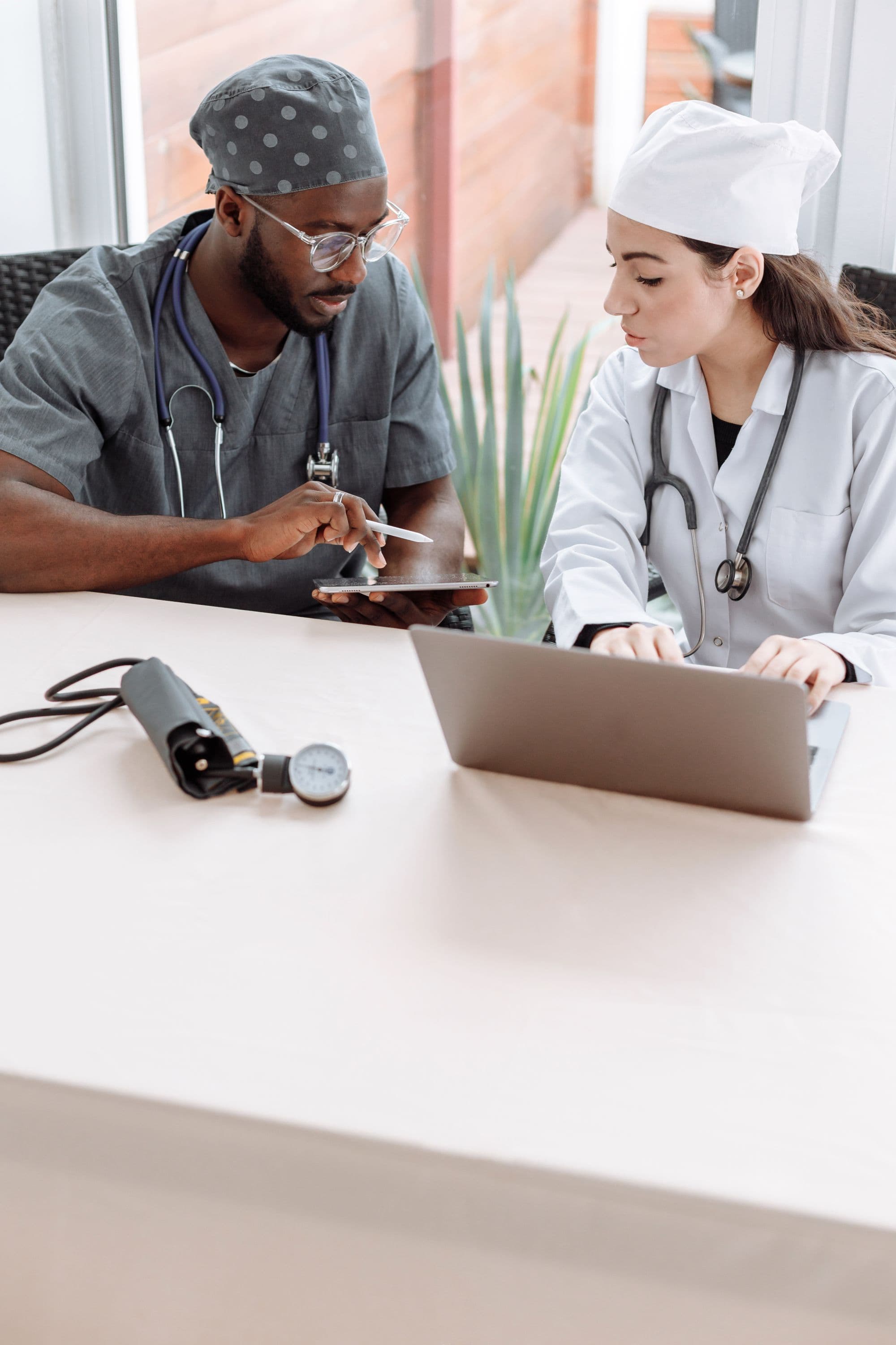 Healthcare professionals collaborating over a tablet. Demonstration imagery — not Peak Mark staff.